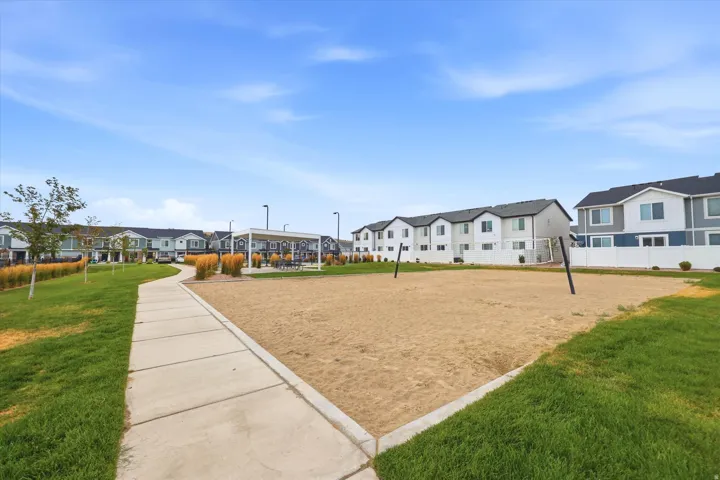 Community sand court with permanent posts, bordered by a concrete pathway and manicured lawn