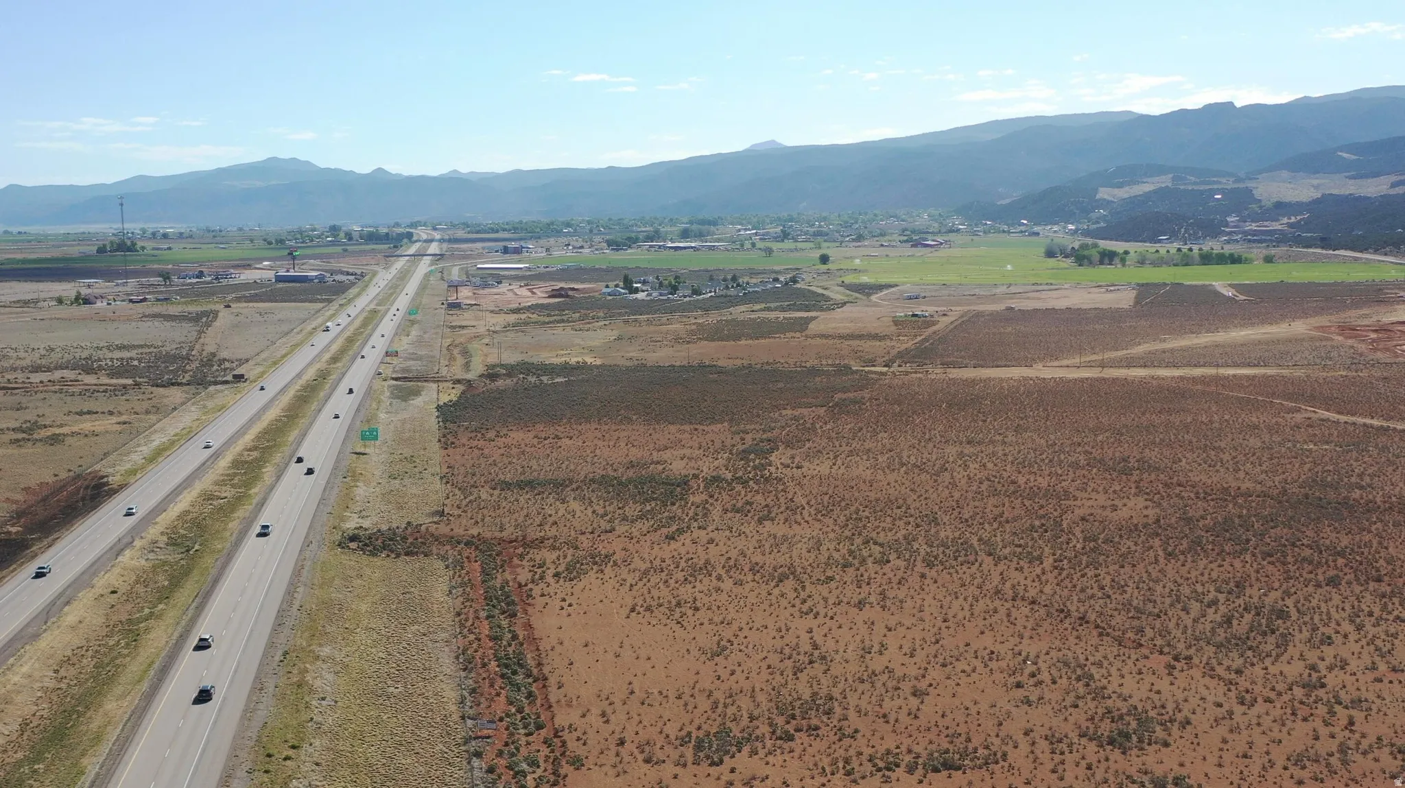 Expansive undeveloped land featuring a major highway frontage, arid terrain with sparse vegetation, and distant mountain ranges
