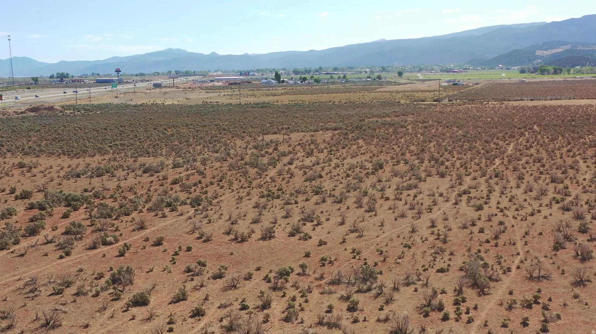Expansive undeveloped land with natural scrub brush and distant mountain ranges