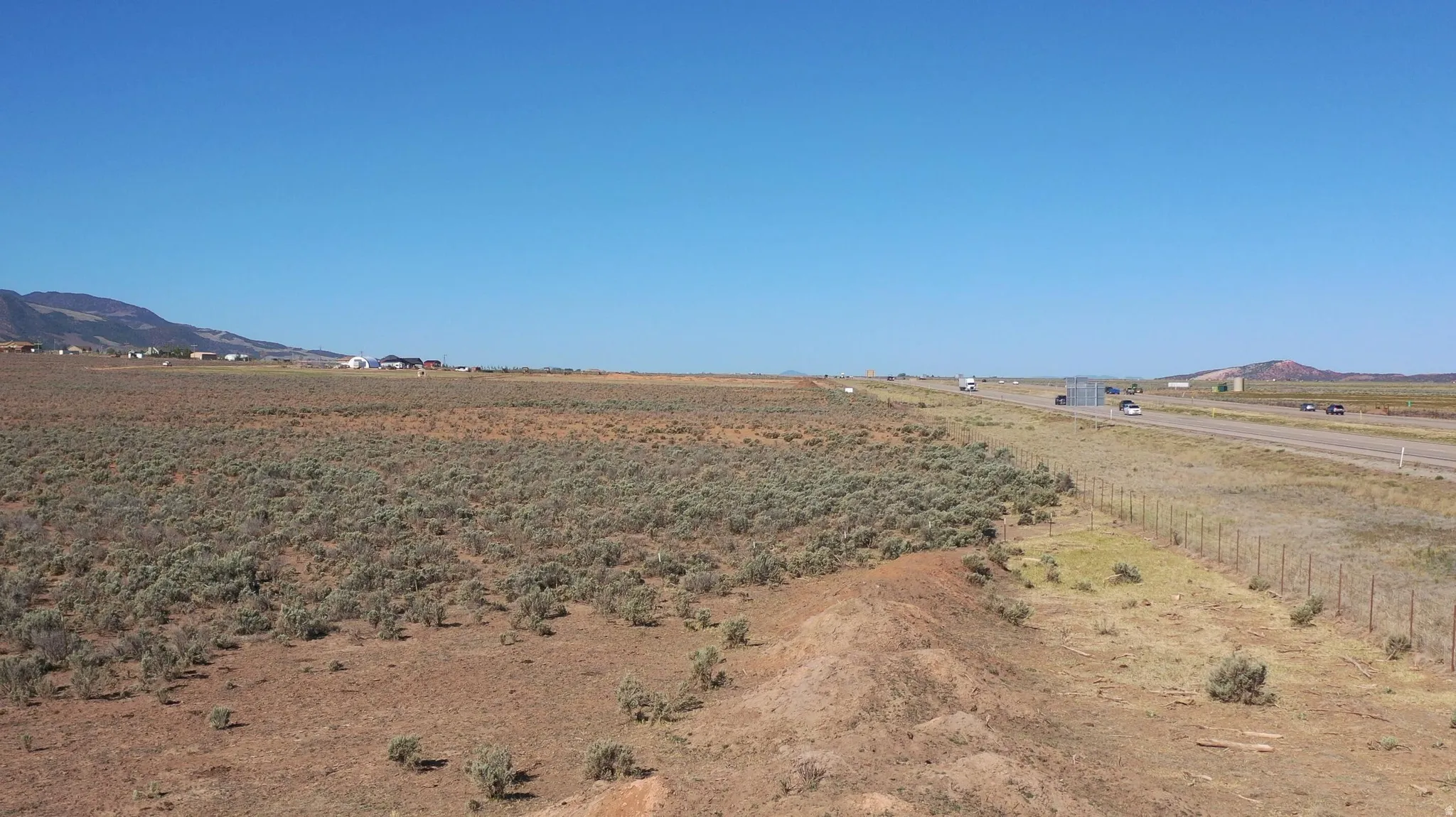 Expansive undeveloped land featuring natural shrubbery and distant mountains