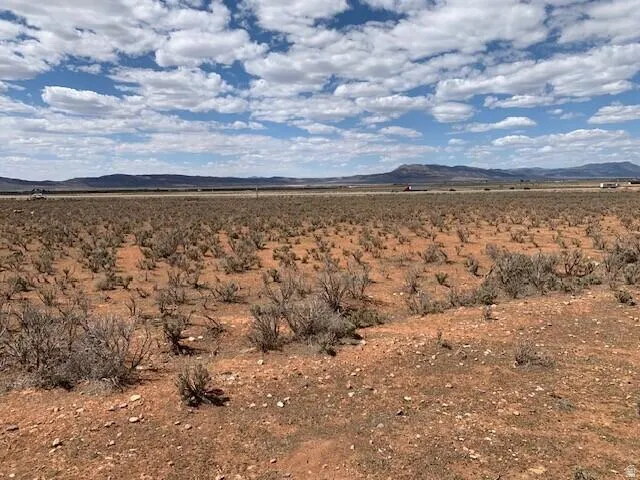 Expansive desert landscape featuring reddish-brown soil and sparse shrubbery