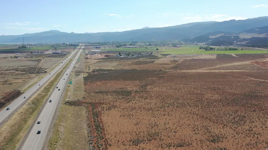 Expansive undeveloped land featuring a major highway frontage, arid terrain with sparse vegetation, and distant mountain ranges