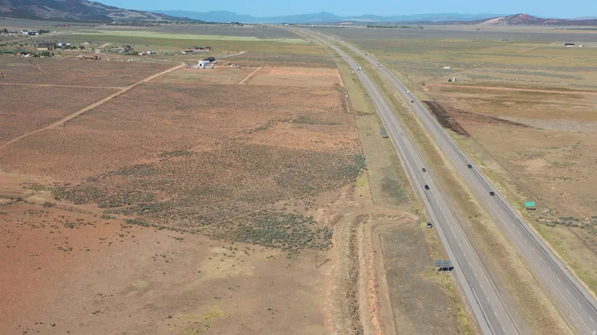 Expansive rural land parcel featuring a visible highway, distant mountains, and scattered brush