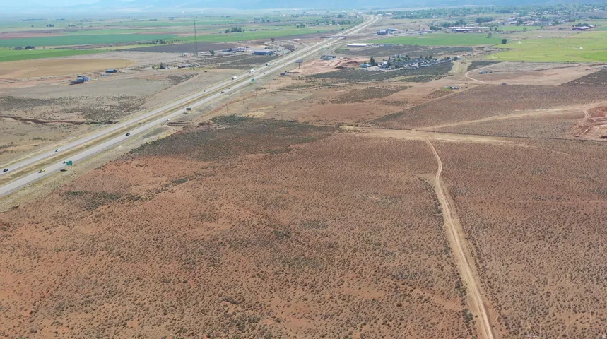 Expansive undeveloped land with visible highway access and distant green agricultural fields