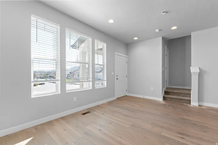 Light wood-finish flooring, recessed lighting, multiple windows with blinds, and white trim throughout