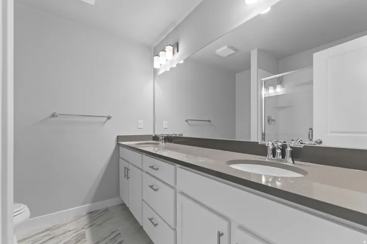 Dual vanity with undermount sinks, gray countertops, and extensive mirror