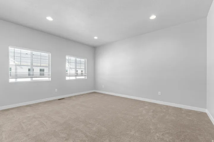 Neutral wall color, recessed lighting, and soft carpet flooring