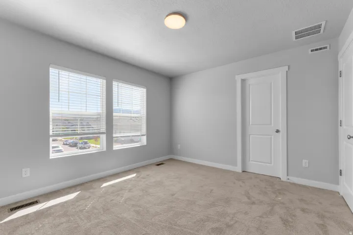Soft gray walls with dual windows, beige carpeting, white trim, and a flush-mount ceiling light