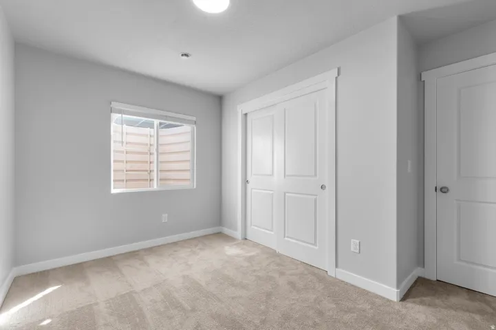 Carpeted flooring, window with blinds, white trim, white paneled doors, and ceiling-mounted light fixture