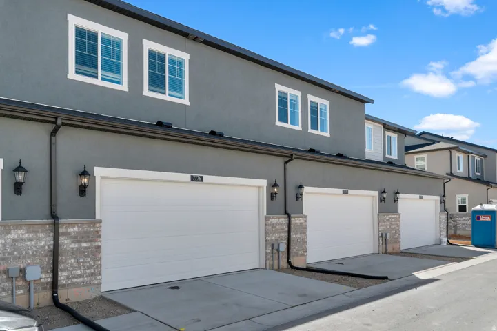Exterior featuring a stucco finish, individual garage doors, and decorative brick accents
