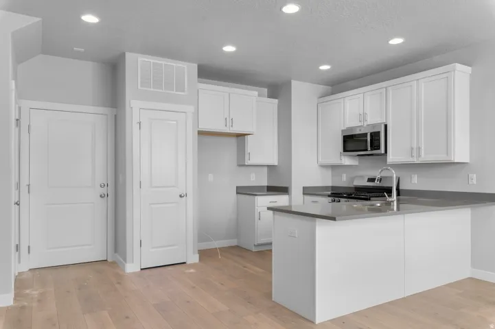 Kitchen featuring light wood-finish flooring, recessed lighting, white cabinetry, a kitchen island, and stainless steel appliances
