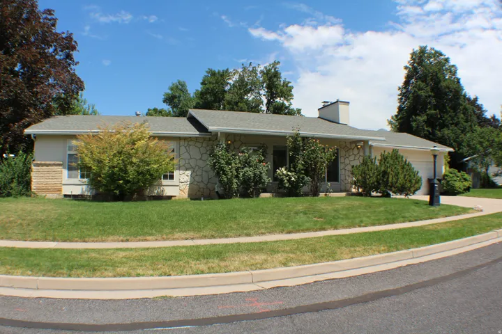 Ranch-style residence featuring a stone and stucco exterior, an attached garage, and an asphalt shingle roof