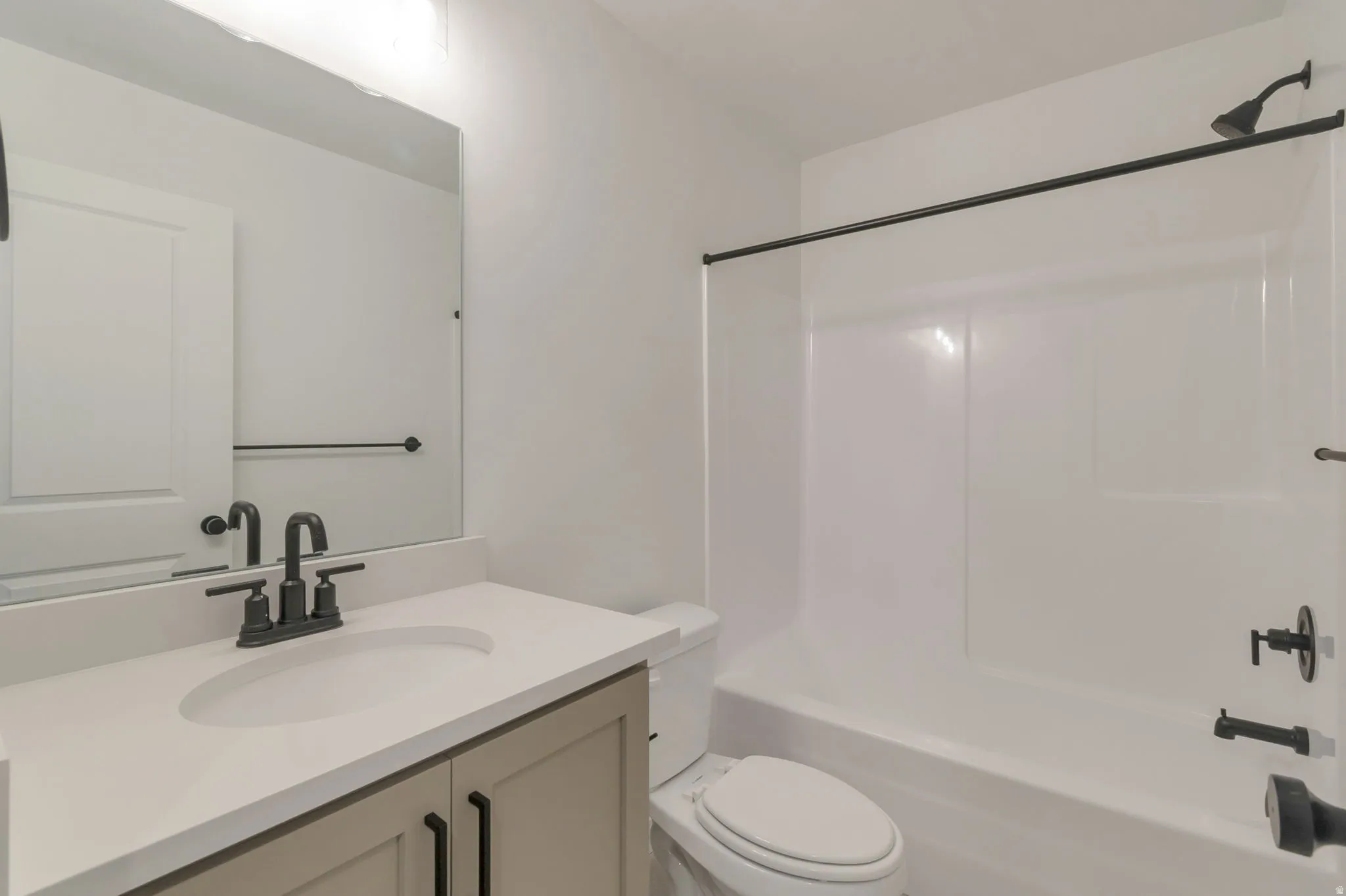 Modern bathroom featuring a single vanity with stone-finish countertop, undermount sink, and matte black fixtures