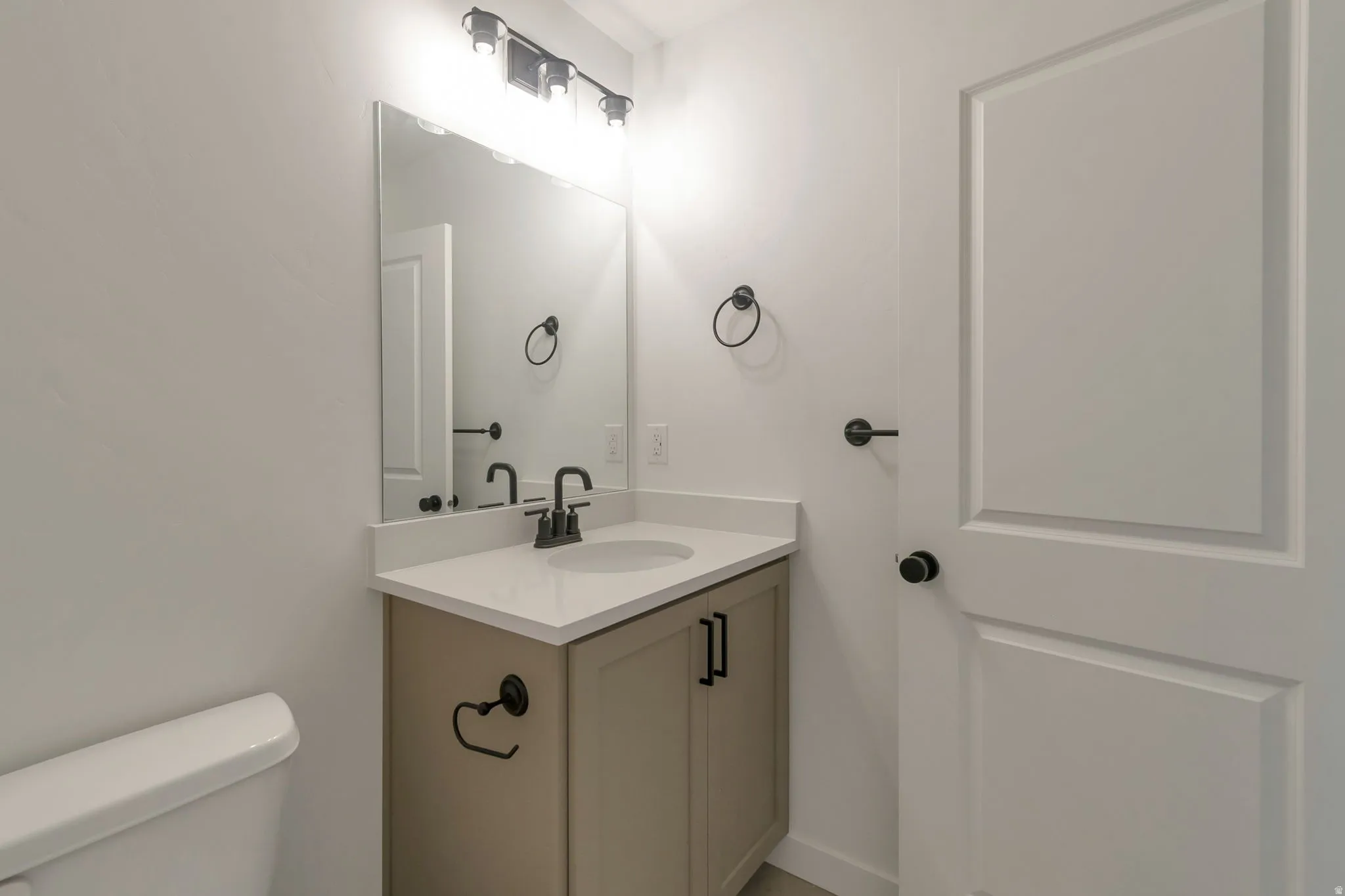 Bathroom vanity featuring a light beige cabinet, a white countertop with an integrated sink, and matte black fixtures