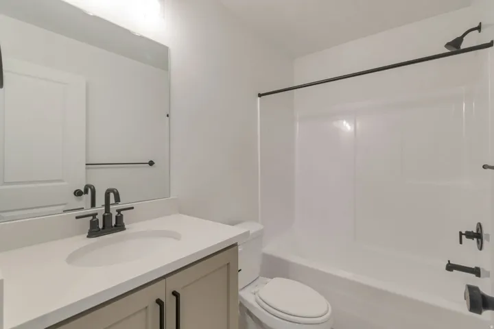 Modern bathroom featuring a single vanity with stone-finish countertop, undermount sink, and matte black fixtures