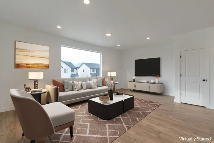 Spacious living area featuring a large picture window, recessed lighting, wood-finish flooring, a contemporary door with black hardware, and crisp white walls