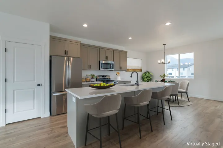 Open-concept kitchen featuring an island with seating, stainless steel appliances, contemporary cabinetry, and wood-finish flooring throughout