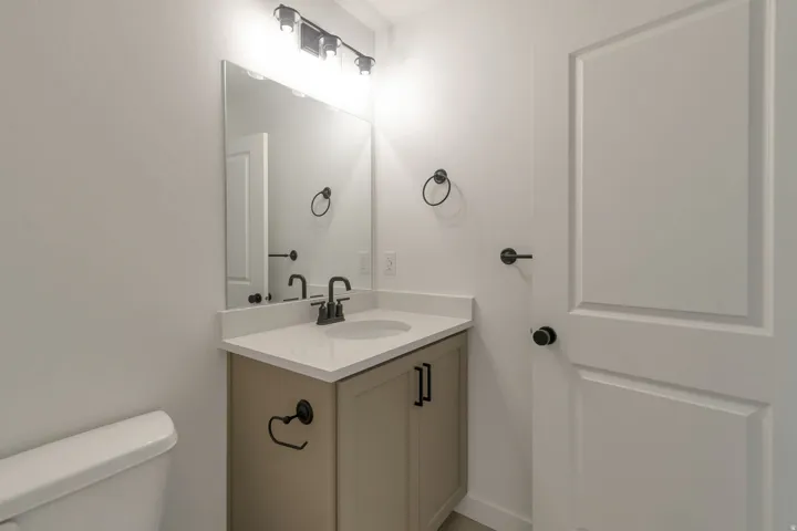 Bathroom vanity featuring a light beige cabinet, a white countertop with an integrated sink, and matte black fixtures