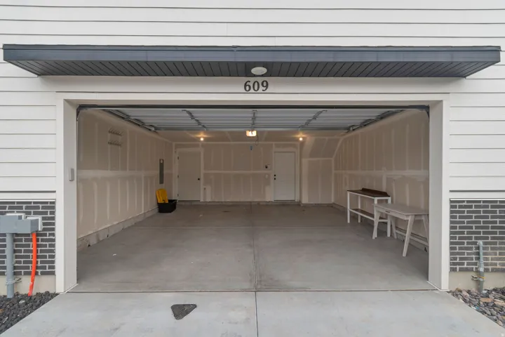 Spacious two-car garage with a concrete floor, interior lighting, and two entry doors