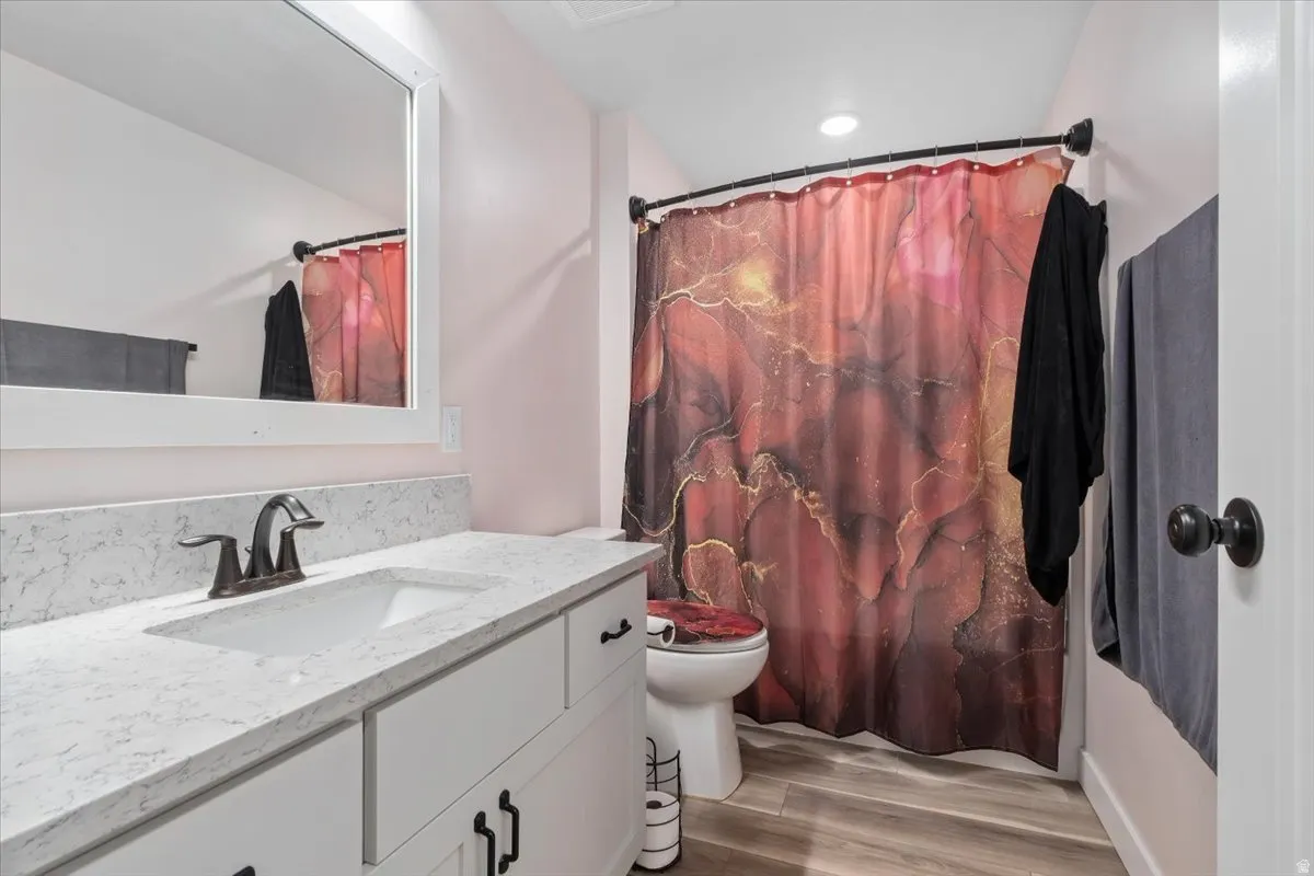 Bathroom featuring a single vanity with a white countertop, undermount sink, and bronze-finish faucet