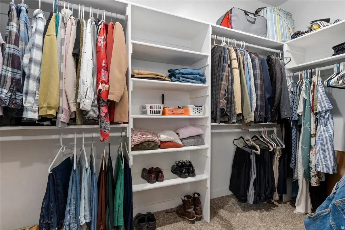 Built-in closet system featuring multiple hanging rods, white shelving, and carpet flooring