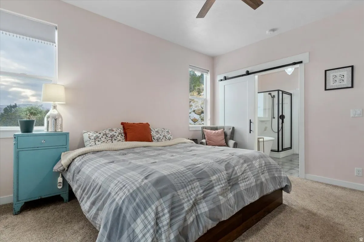 Bedroom featuring neutral wall paint, carpet flooring, a ceiling fan, and a window providing natural light