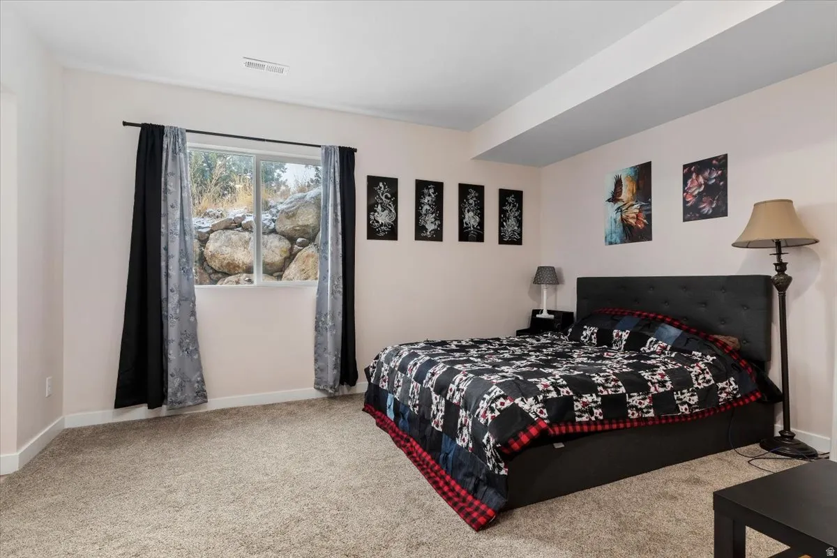 Bedroom with neutral-toned carpeting, light-colored walls, and a window with a rock and natural landscape backdrop