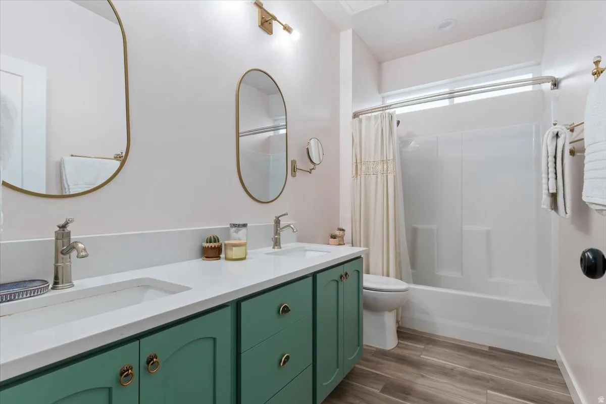 Bathroom featuring a double vanity with green cabinetry, white countertops, and contemporary oval mirrors