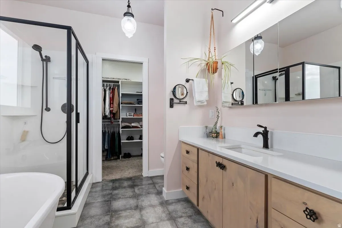 Bathroom featuring a freestanding tub, glass-enclosed shower with black trim, and a wood-finish vanity with a built-in sink and matte black faucet
