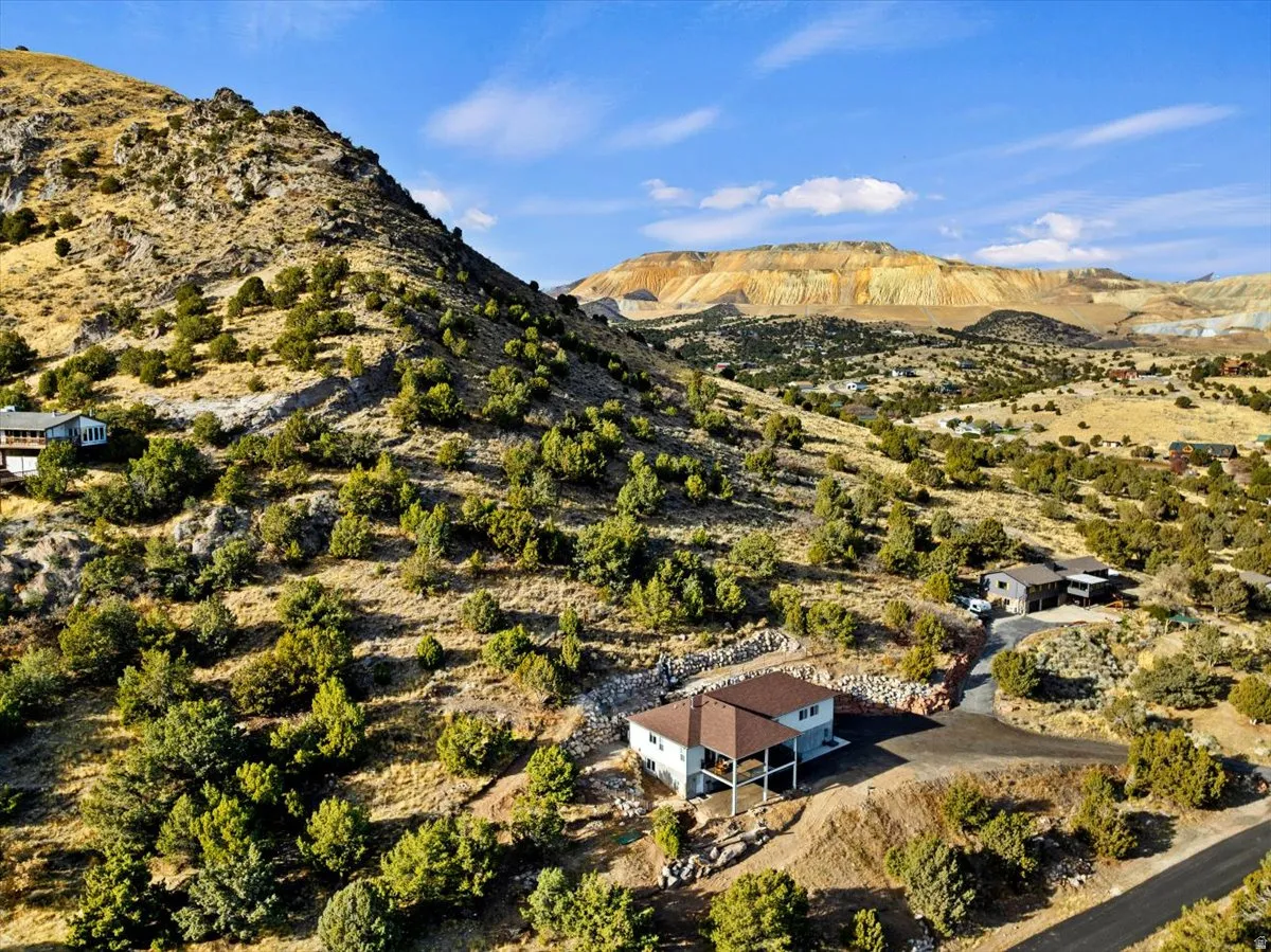 Hillside property featuring a multi-level residence with a covered patio, a detached garage, and a paved driveway