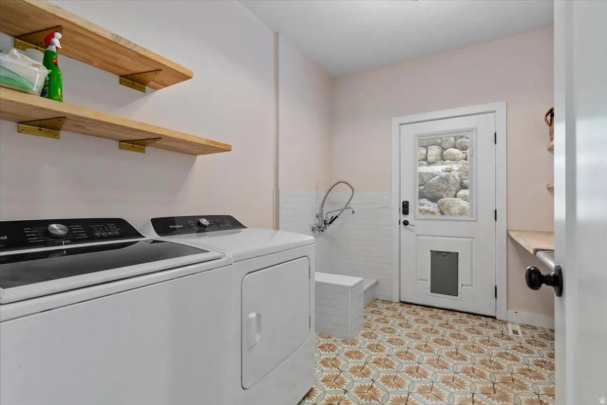 Laundry area with patterned floor tile, white appliances, and wall-mounted shelving