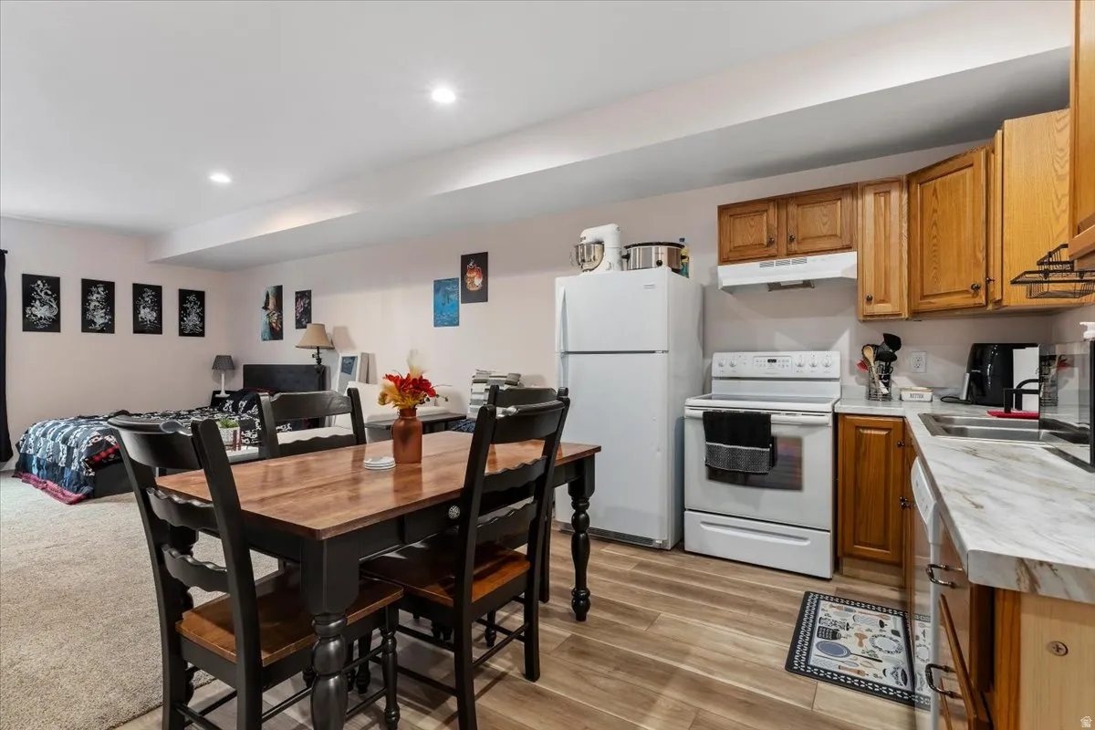 Open-concept living space with recessed lighting, wood-finish flooring, and a full kitchen featuring a white refrigerator, range, and wood cabinetry
