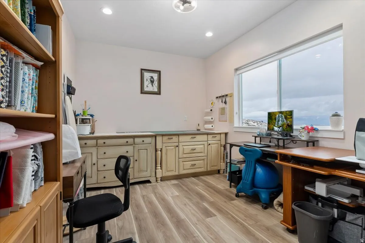 Spacious room featuring light-toned walls, wood-finish flooring, and recessed lighting