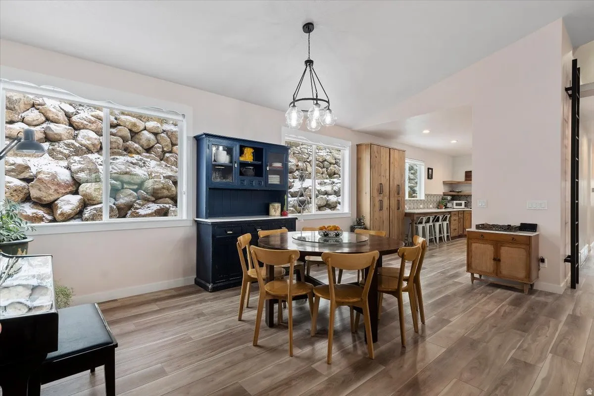 Dining area featuring wood-finish flooring, a contemporary chandelier, and multiple windows