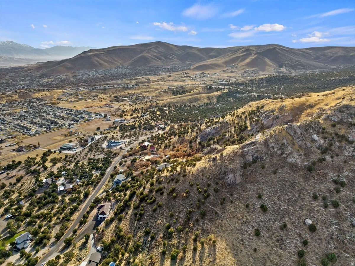 Expansive aerial of a mountainous landscape with sparse vegetation and residential development
