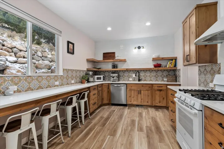Spacious kitchen featuring wood-finish flooring, custom wood cabinetry, and a unique patterned backsplash