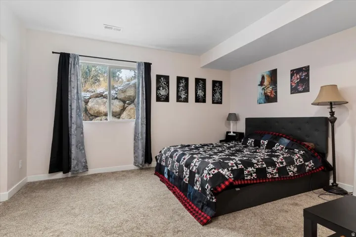 Bedroom with neutral-toned carpeting, light-colored walls, and a window with a rock and natural landscape backdrop