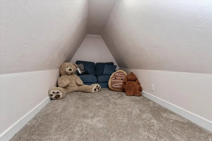 Carpeted attic space featuring sloped ceilings and white baseboards