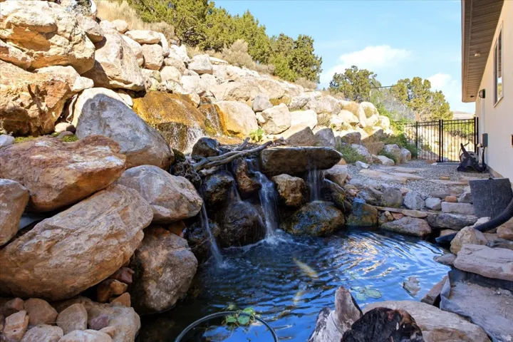 Rock-lined water feature with multiple cascades, a deep pond, and integrated natural stone elements