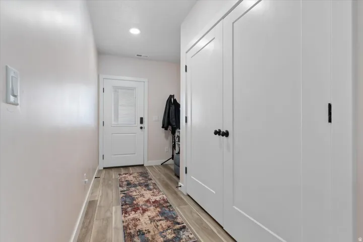 Entryway featuring wood-finish flooring, recessed lighting, and a solid-panel door with integrated blinds