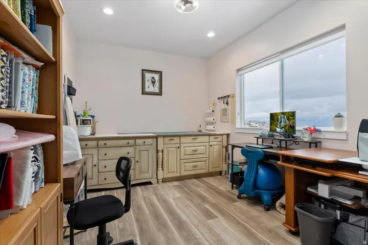 Spacious room featuring light-toned walls, wood-finish flooring, and recessed lighting