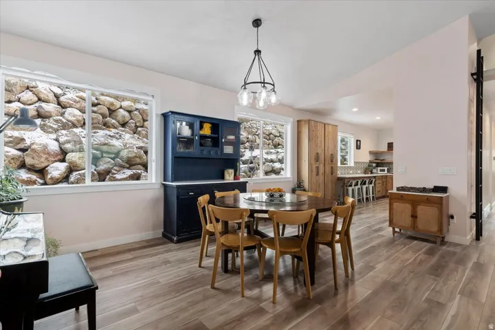 Dining area featuring wood-finish flooring, a contemporary chandelier, and multiple windows