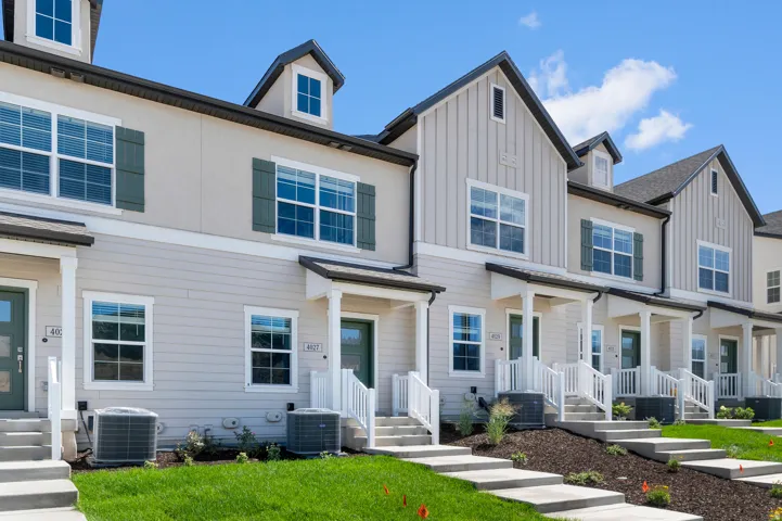 Townhome exterior featuring board-and-batten and horizontal siding, with dormer windows and front porches with white railings