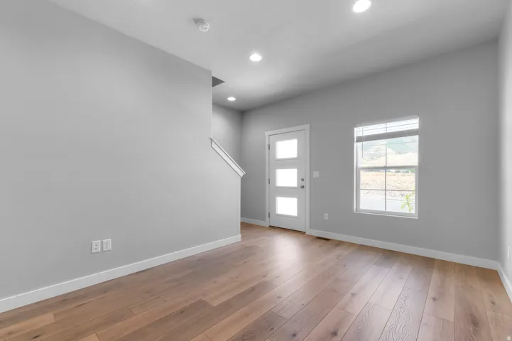 Wood-finish flooring, recessed lighting, and a white entry door with frosted glass panels