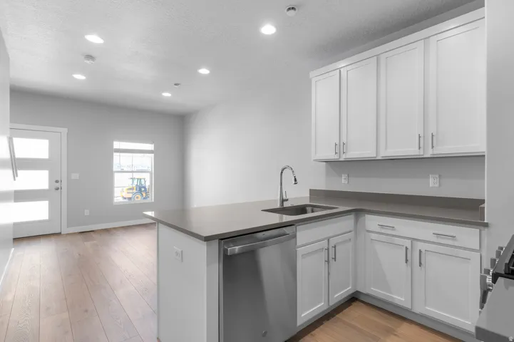 Kitchen featuring white cabinetry, stainless steel appliances, a stainless steel sink, and light-toned countertops