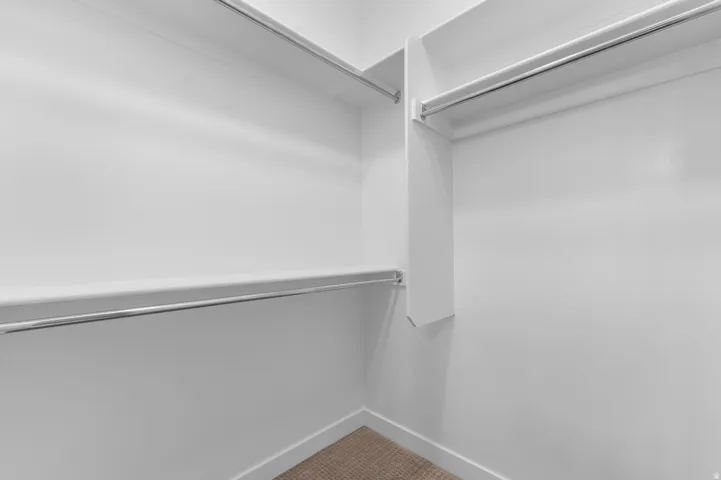 White shelving system with chrome hanging rods and a carpeted floor