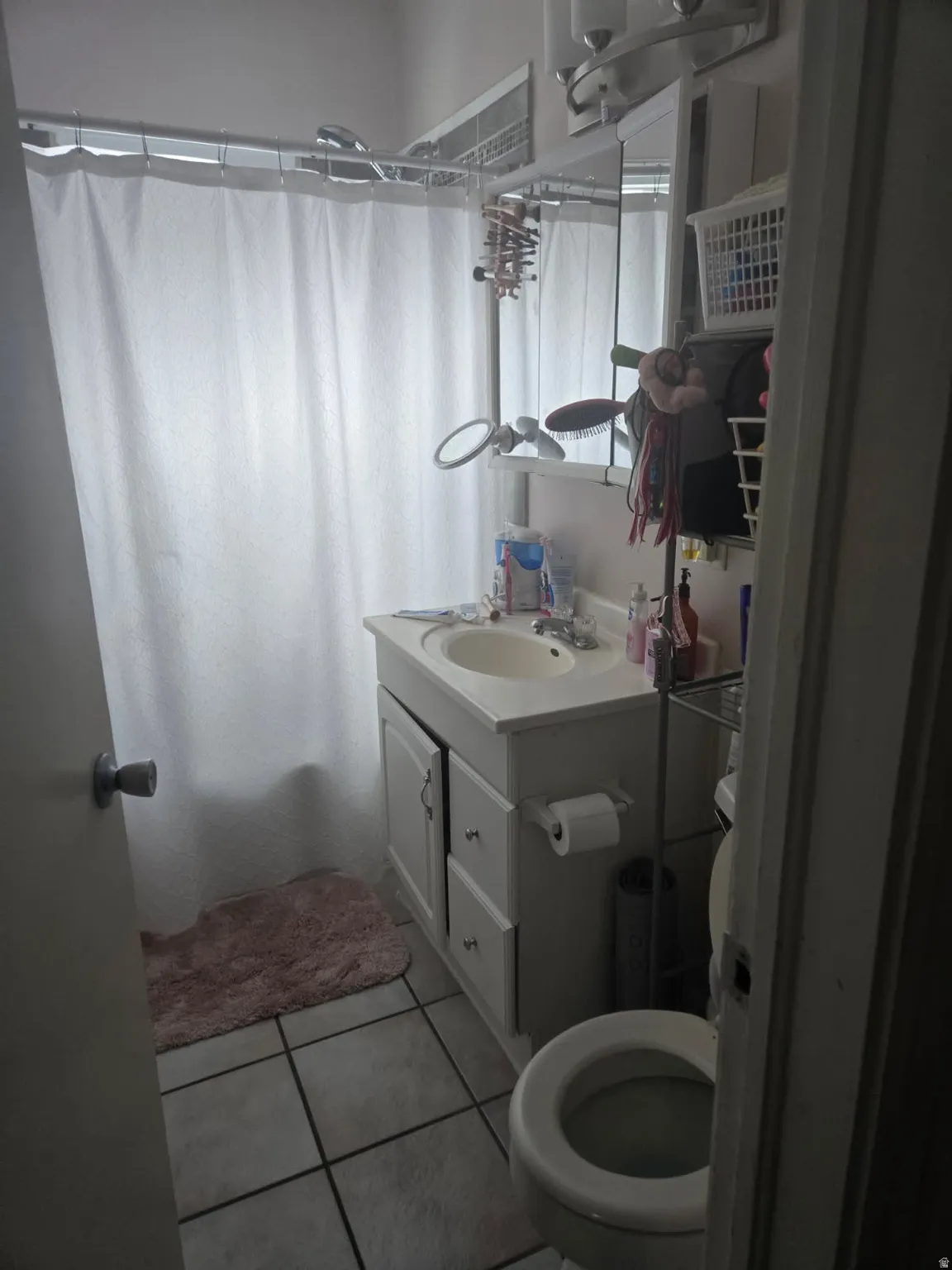 Bathroom featuring a vanity with integrated sink, coordinating base cabinetry, mirrored medicine cabinet, and tile flooring