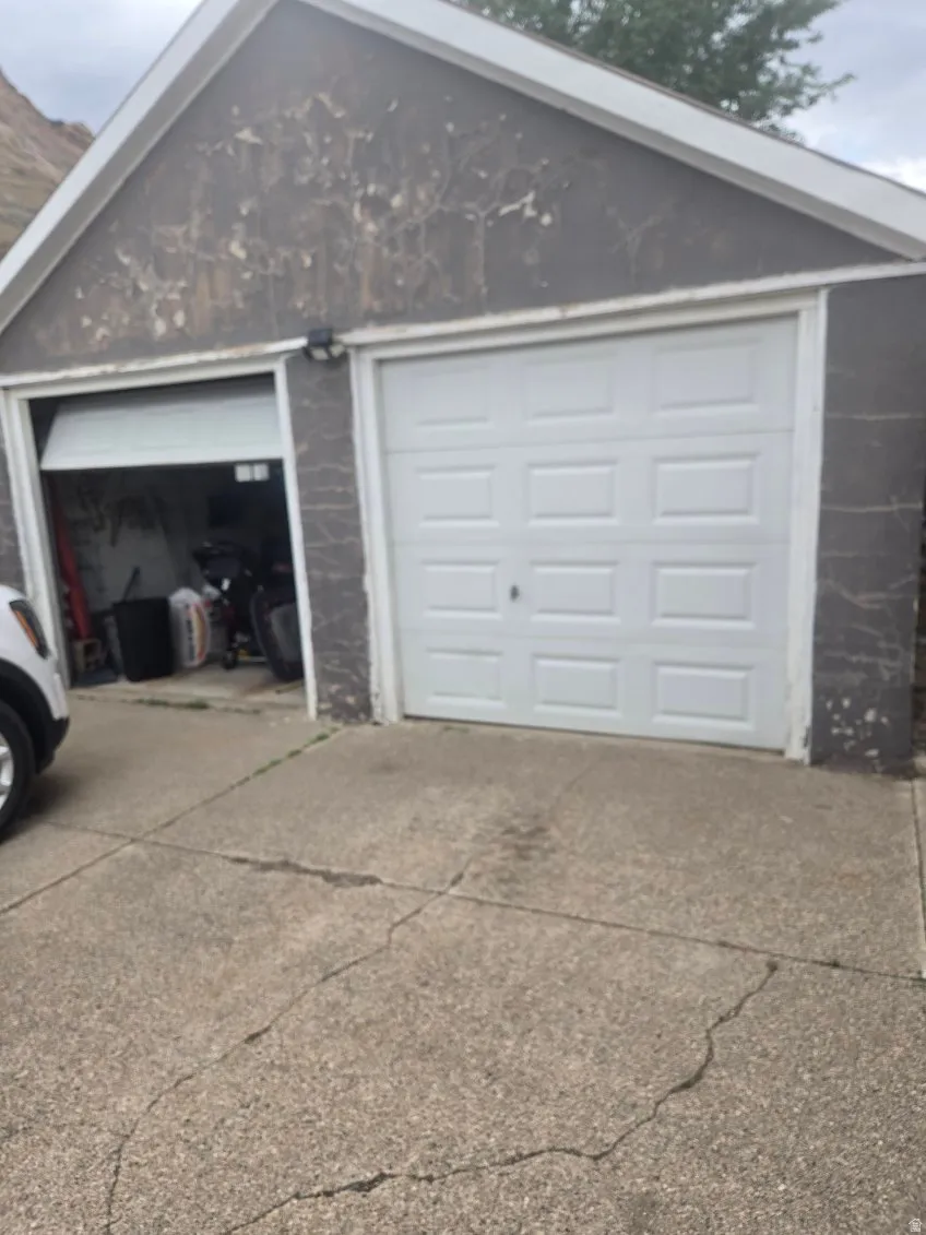Detached two-car garage featuring panel-style doors, exterior wall sconce lighting, and a concrete driveway