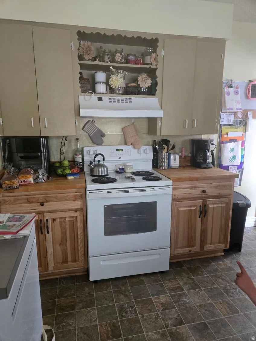 Kitchen featuring a white electric range, wood-finish countertops, and upper and lower cabinetry