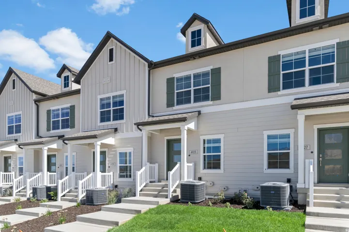 Exterior featuring board and batten siding, stucco finishes, individual covered front porches, dormer windows, and concrete walkways
